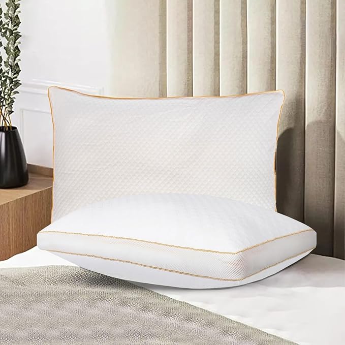 White pillow with gold trim on a bed in a bedroom setting