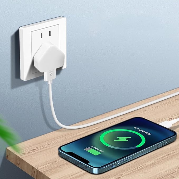 Phone charging on a wooden surface with a wall outlet in the background