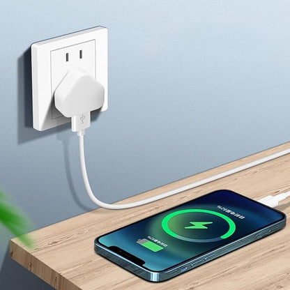 Phone charging on a wooden surface with a wall outlet in the background