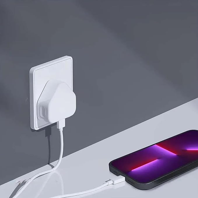 White wall-mounted charging station with a smartphone connected by a cable on a gray background