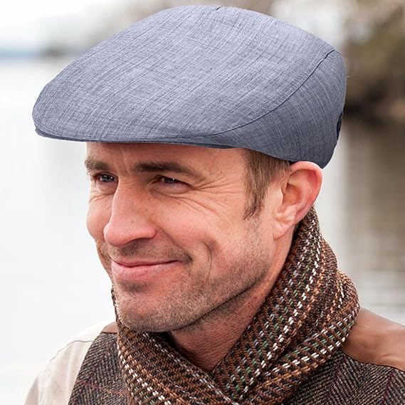 Man wearing a gray flat cap and patterned scarf with a blurred background