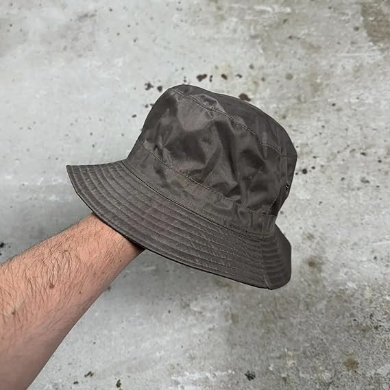 Gray bucket hat held by a person against a concrete background