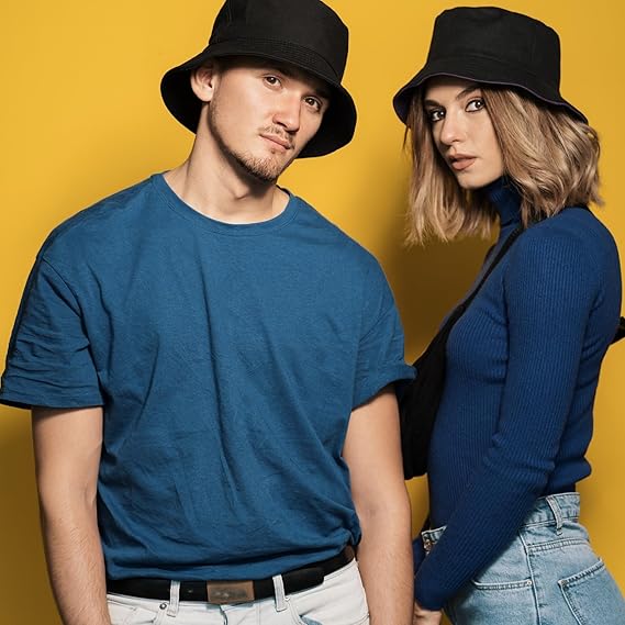 Two people wearing black bucket hats against a yellow background